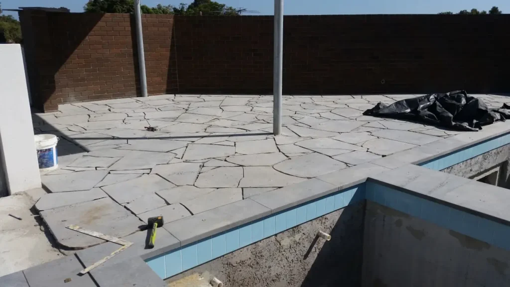 Professional natural stone paving installed around a residential swimming pool in Perth